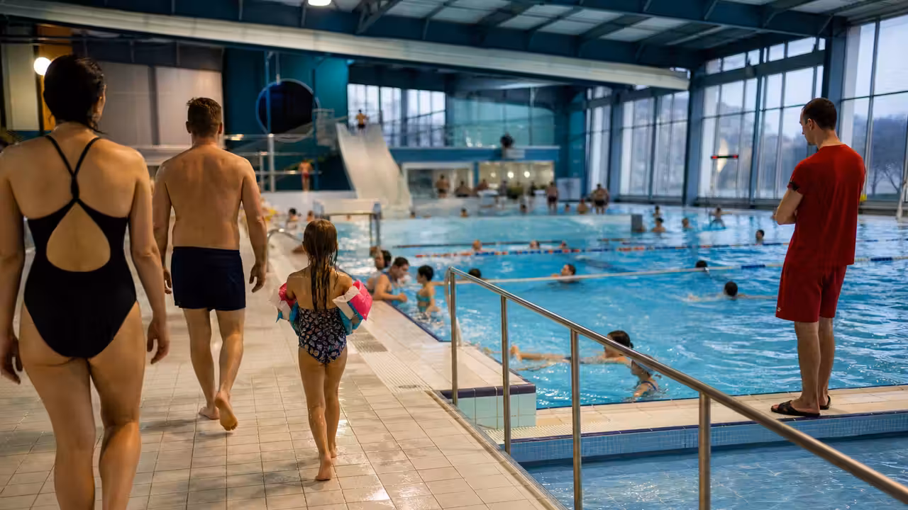 Bassin couvert d’une piscine publique animé pendant les vacances, avec nageurs et familles sur les plages