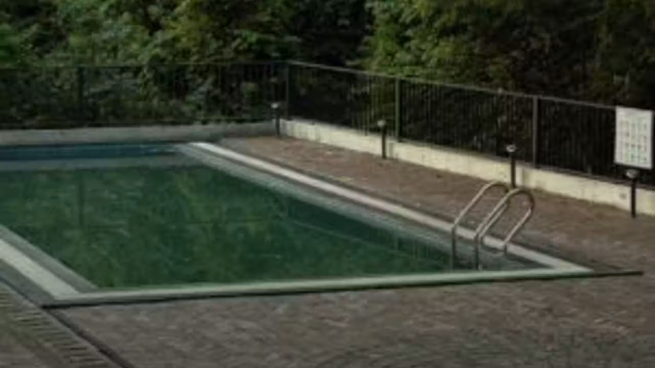 Bassin sportif couvert vide avec lignes d’eau, grandes baies vitrées et gradins d’une piscine municipale