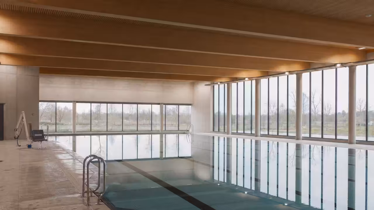 Façade contemporaine d’un centre aquatique municipal avec baies vitrées et bassin intérieur lumineux