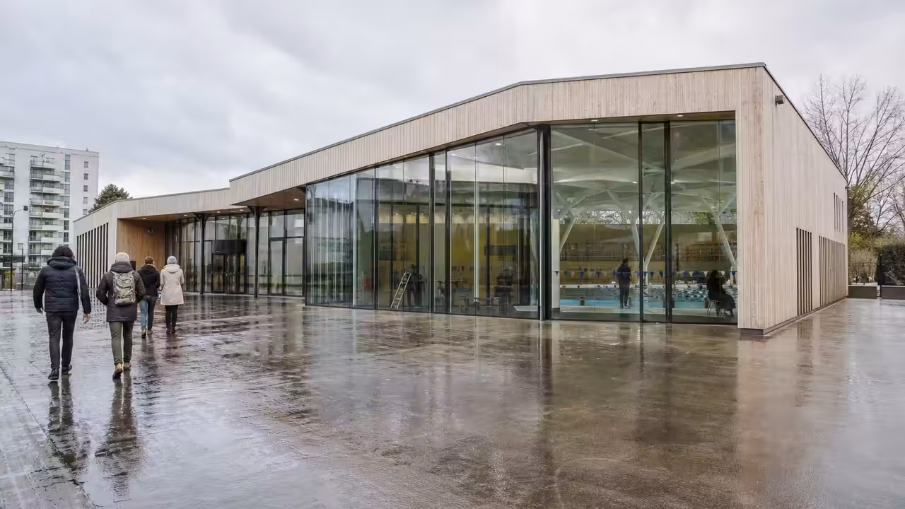 Bassin intérieur lumineux d’un centre aquatique municipal moderne, avec lignes de nage et baies vitrées