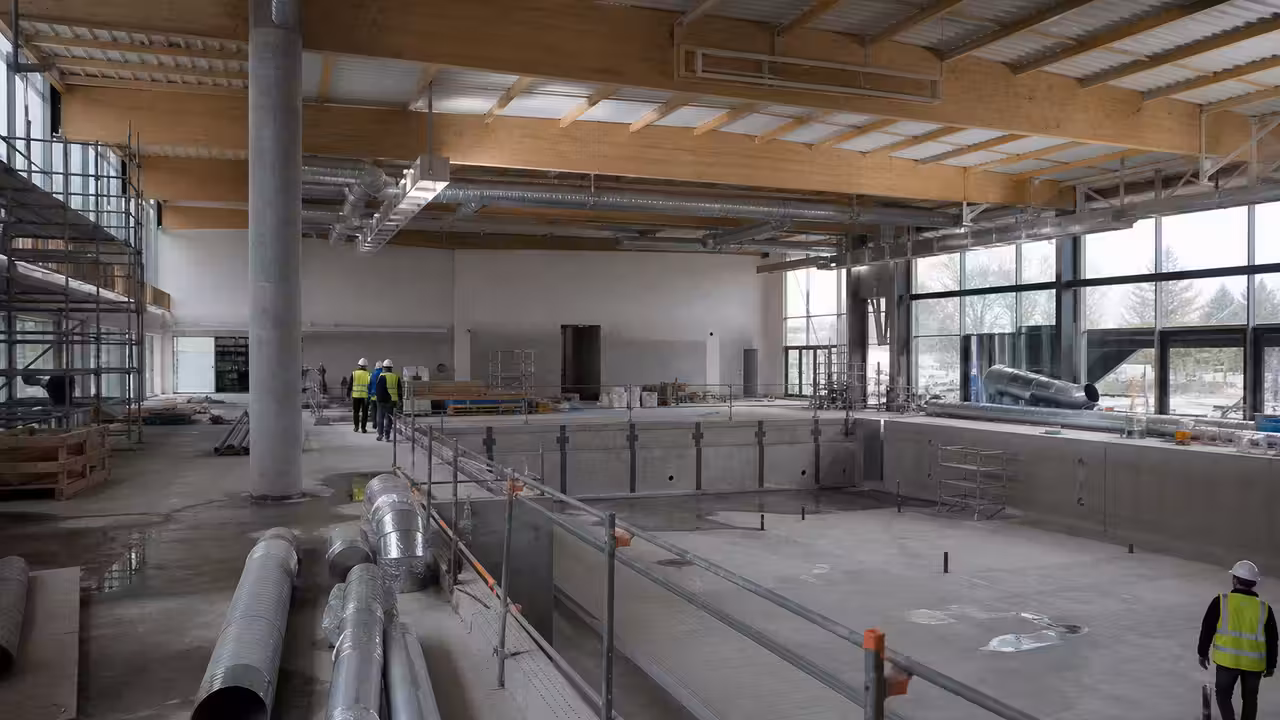 Bassin municipal couvert en travaux, avec charpente technique, couloirs de nage et équipements de chantier