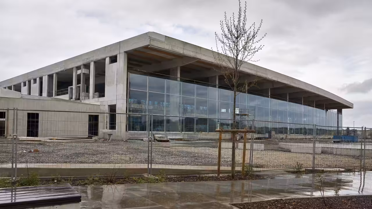 Vue extérieure d’un centre aquatique contemporain avec bassin intérieur visible derrière de grandes baies vitrées