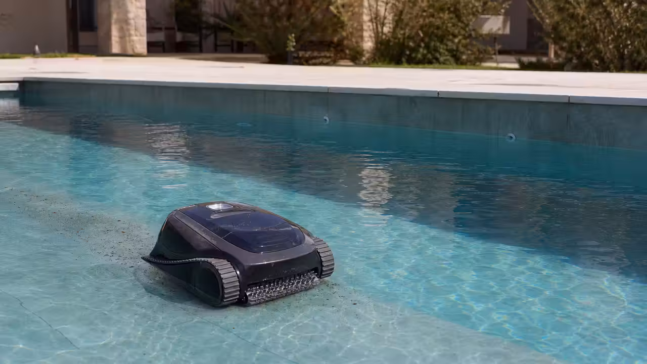 Robot de piscine sans fil nettoyant le fond d’un bassin avec des feuilles et des reflets d’eau