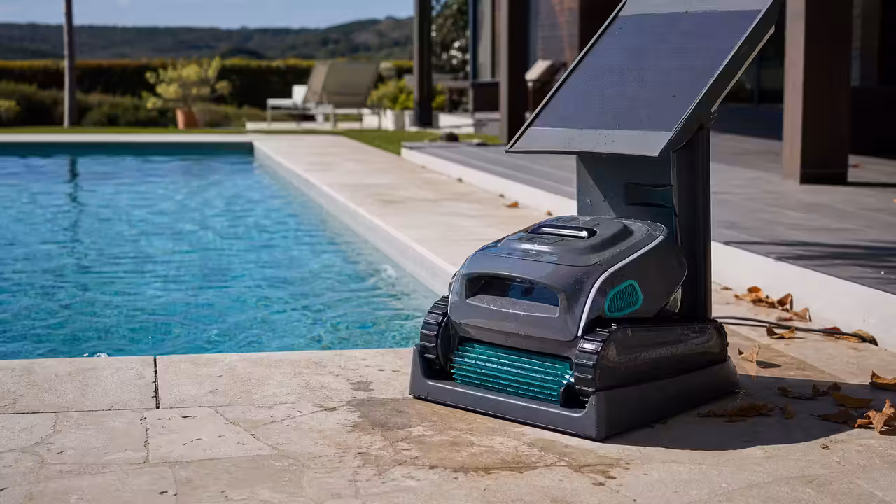 Robot de piscine sans fil posé près d’une station solaire au bord d’un bassin familial ensoleillé