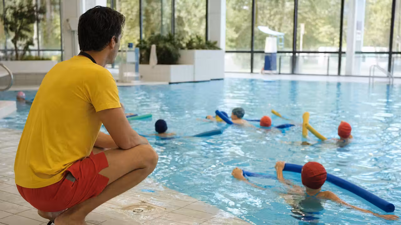 Maître-nageur encadrant un groupe d’enfants lors d’un exercice ludique de sécurité dans une piscine