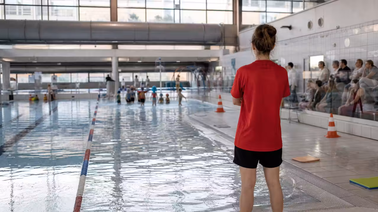 Animation aquatique encadrée dans une piscine publique décorée pour Halloween, avec parents au bord du bassin