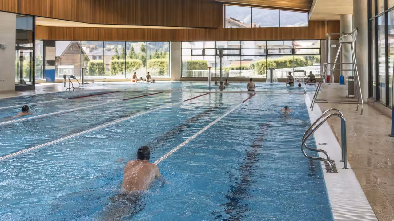 Bassin municipal de 25 mètres avec lignes d’eau et nageurs pendant un créneau de baignade publique