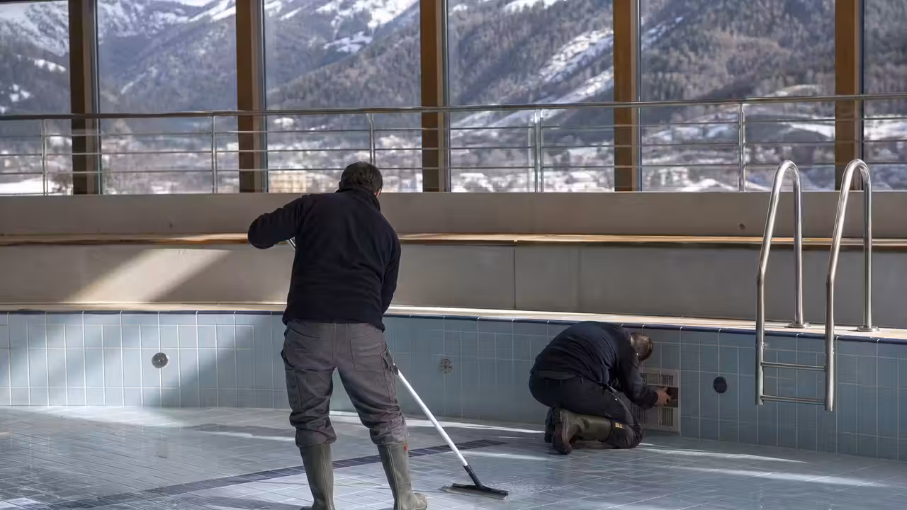 Bassin municipal vidé en hiver, avec agents nettoyant le fond et les parois avant la saison estivale