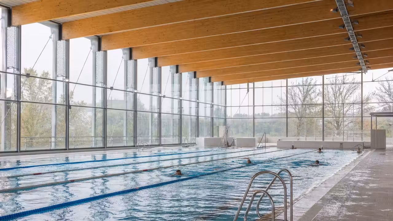 Bassin intérieur d’un centre aquatique municipal moderne, lumineux et sobrement aménagé