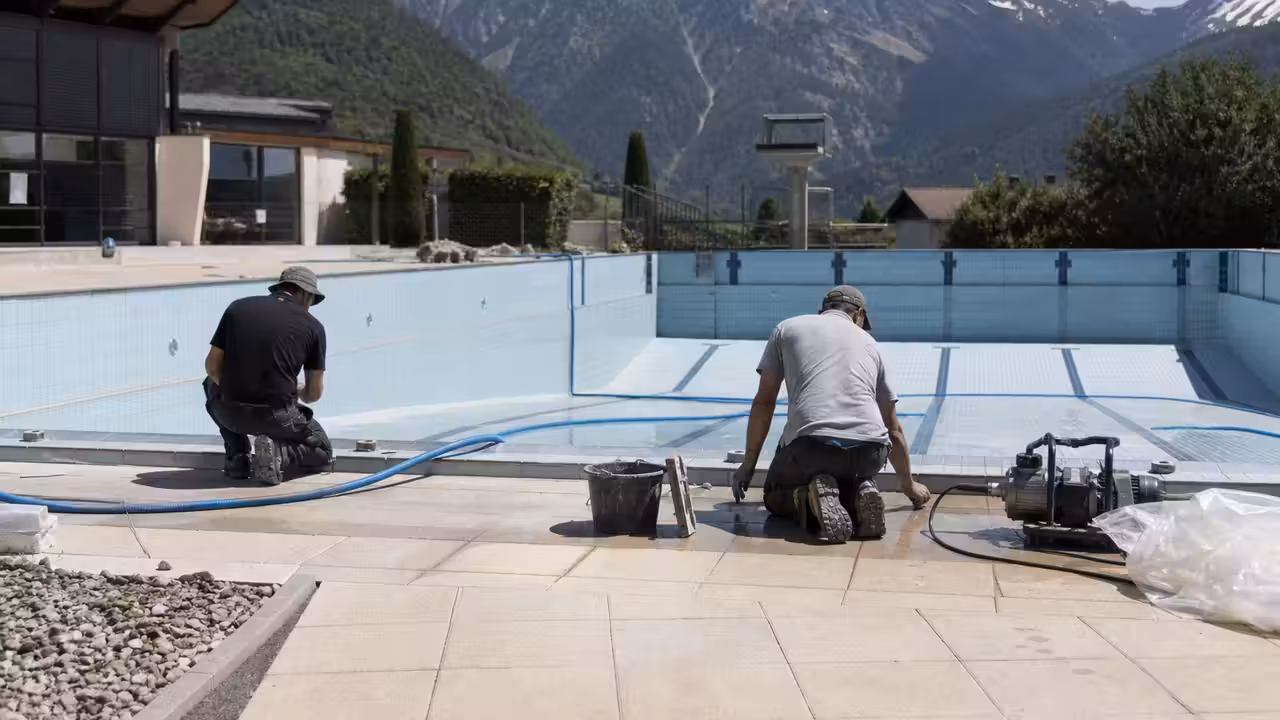 Piscine municipale de montagne en cours de modernisation avec installations techniques et sommets alpins en arrière-plan