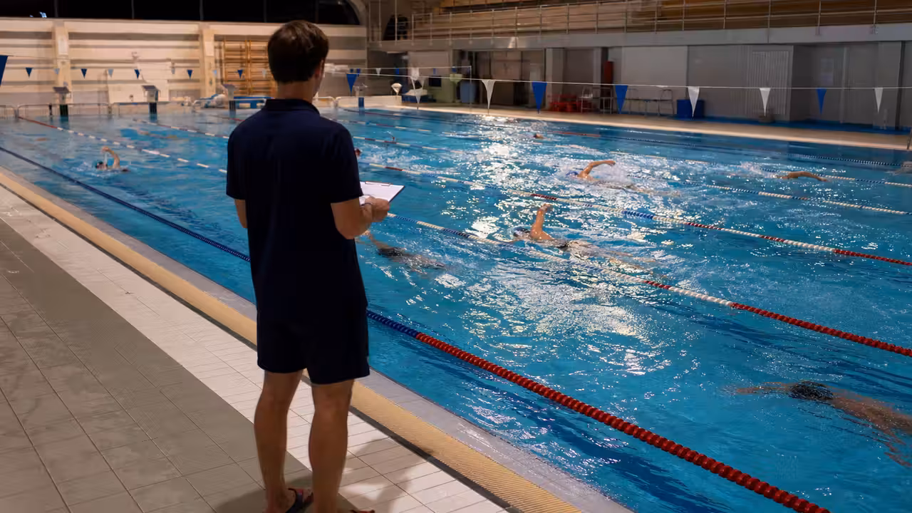 Nageurs d’un club à l’entraînement dans un bassin municipal avec plusieurs lignes d’eau réservées