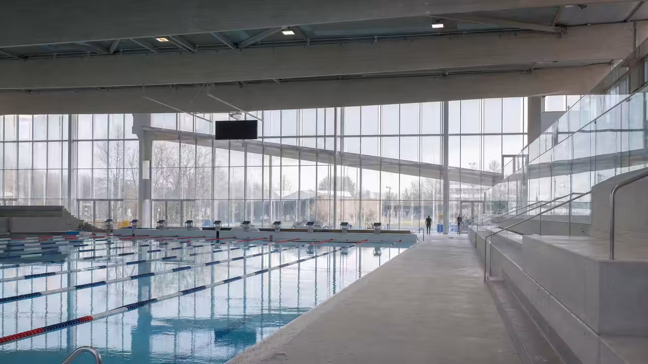 Bassin couvert de 50 mètres avec lignes de nage et plages minérales dans un centre aquatique moderne