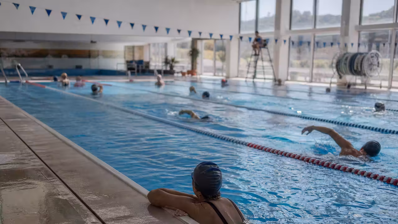 Nageurs adultes participant à un relais solidaire dans les couloirs d’une piscine publique couverte