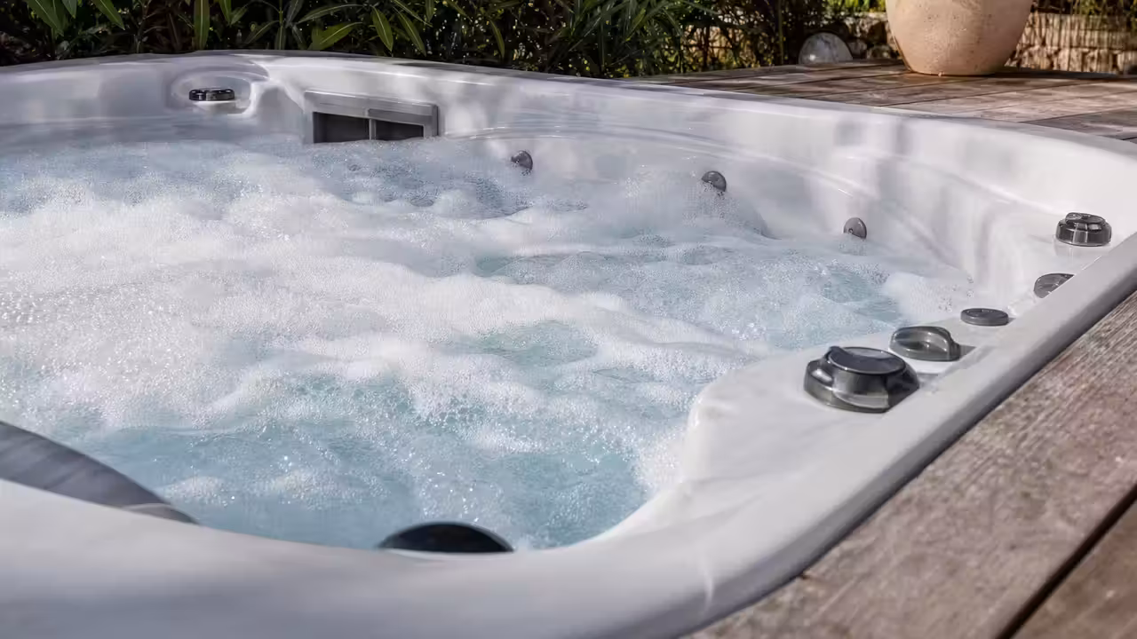 Surface d'un spa extérieur recouverte d'une mousse blanche dense près des jets d'eau