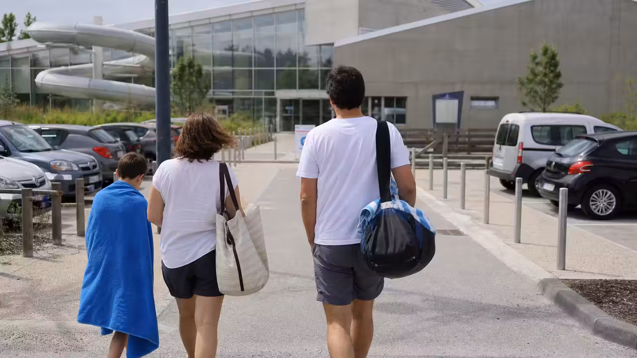 Parking situé près d’un centre aquatique, avec une famille se dirigeant vers l’entrée du bassin