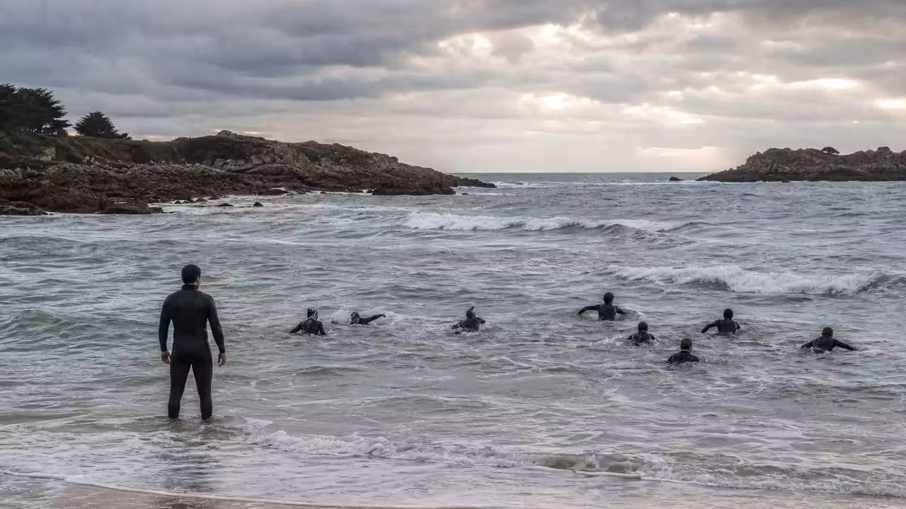 Futurs sauveteurs nageant près du rivage breton sous la surveillance de formateurs dans une mer agitée