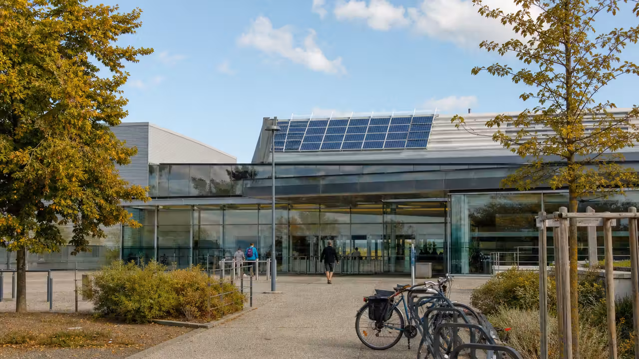 Bassin couvert d’une piscine municipale avec lignes de nage, grandes baies vitrées et équipements techniques discrets