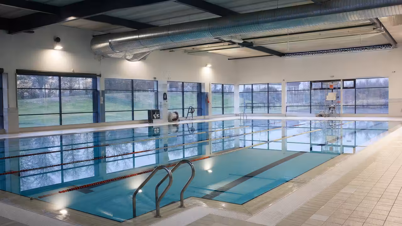 Hall de bassin couvert vide avec baies vitrées, lignes d’eau et système de ventilation en plafond