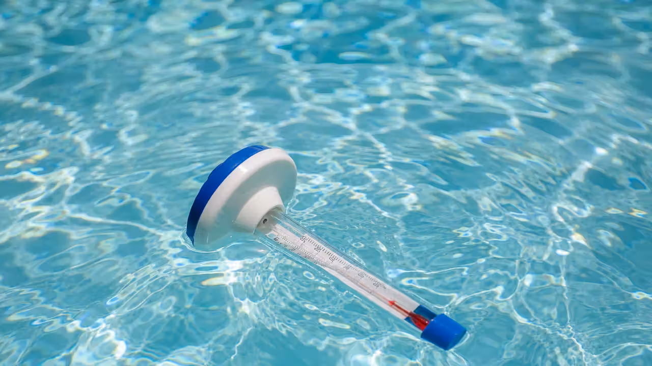 Thermomètre flottant analogique dérivant à la surface d'une piscine turquoise ensoleillée