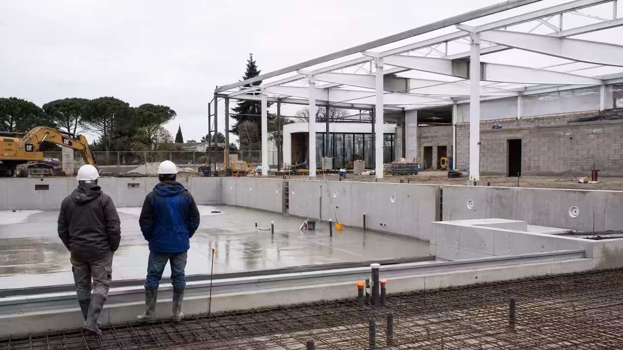 Structure d’une piscine municipale en chantier, avec armatures, béton et engins sous une lumière claire