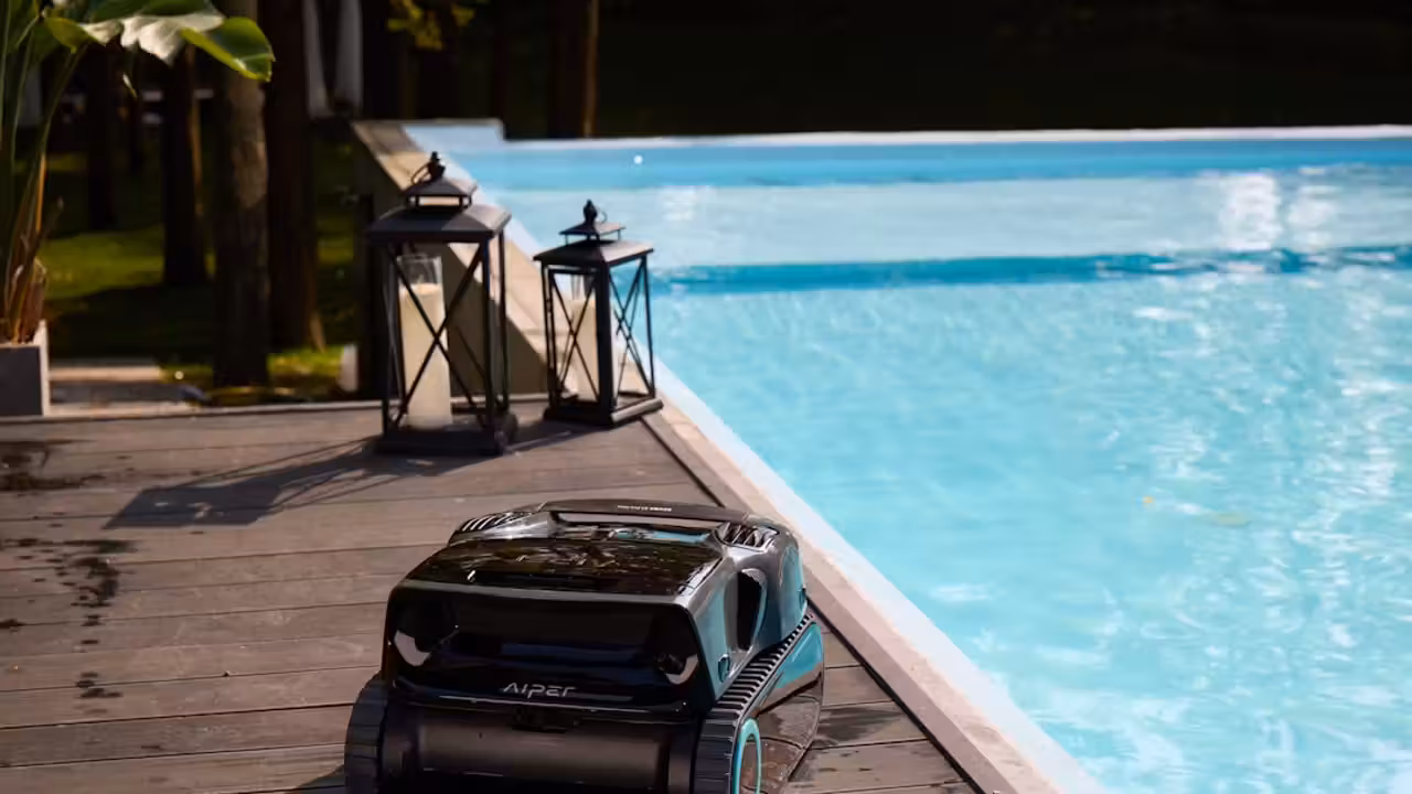 Robot électrique nettoyant le fond carrelé d'une piscine privée, avec panier filtrant visible sous l'eau