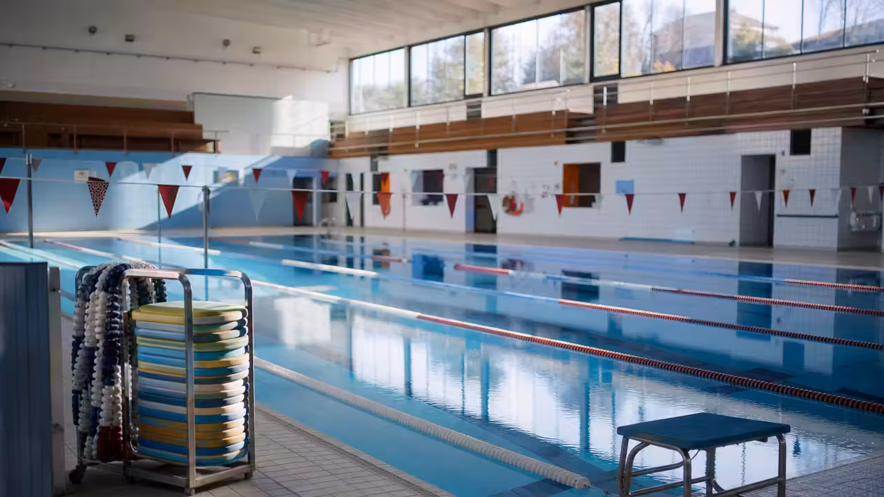 Bassin couvert préparé pour une séance de natation scolaire, avec lignes d’eau et matériel pédagogique rangé