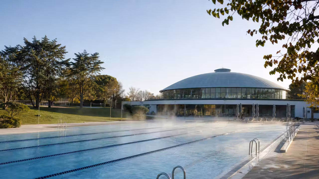 Vue en perspective d’un bassin extérieur de 50 mètres et de ses plages paysagées dans une piscine municipale