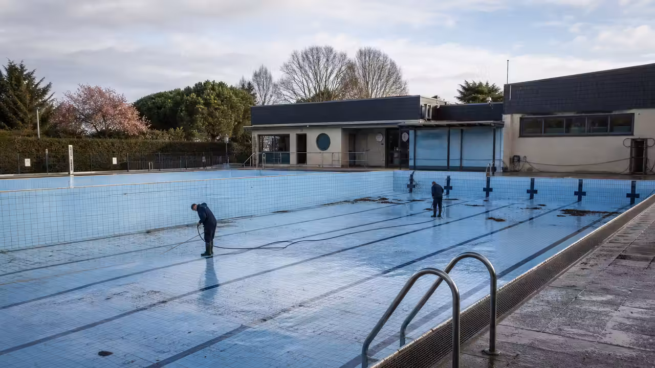 Bassin extérieur d’une piscine municipale préparé avant la saison, avec plages propres et eau calme