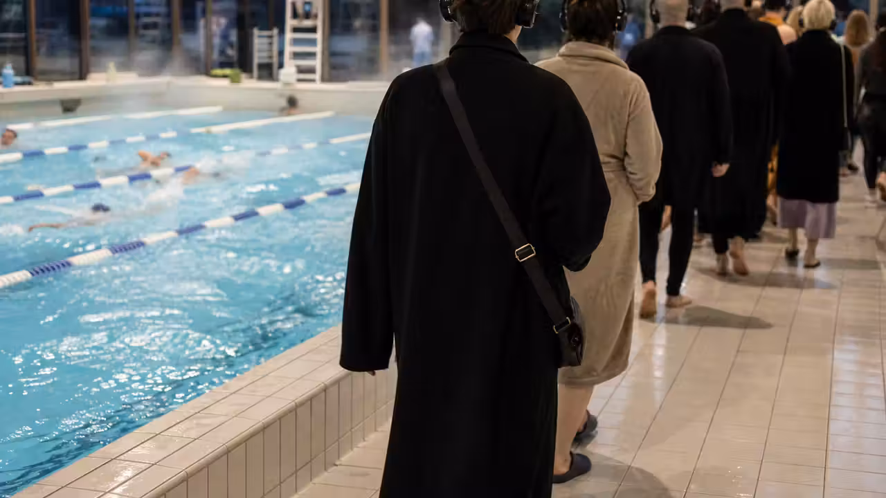 Spectateurs casqués circulant au bord d’un bassin couvert pendant une représentation immersive en soirée
