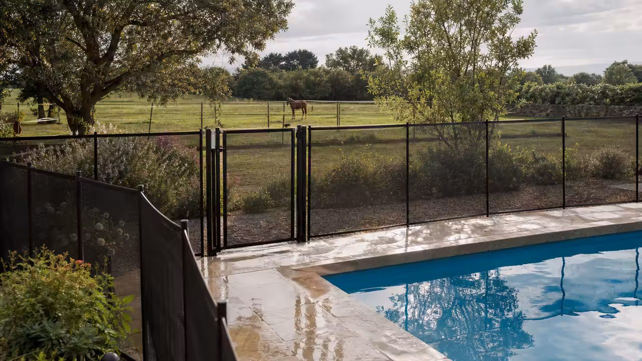 Barrière de sécurité fermée autour d’une piscine privée située à proximité d’un pré rural