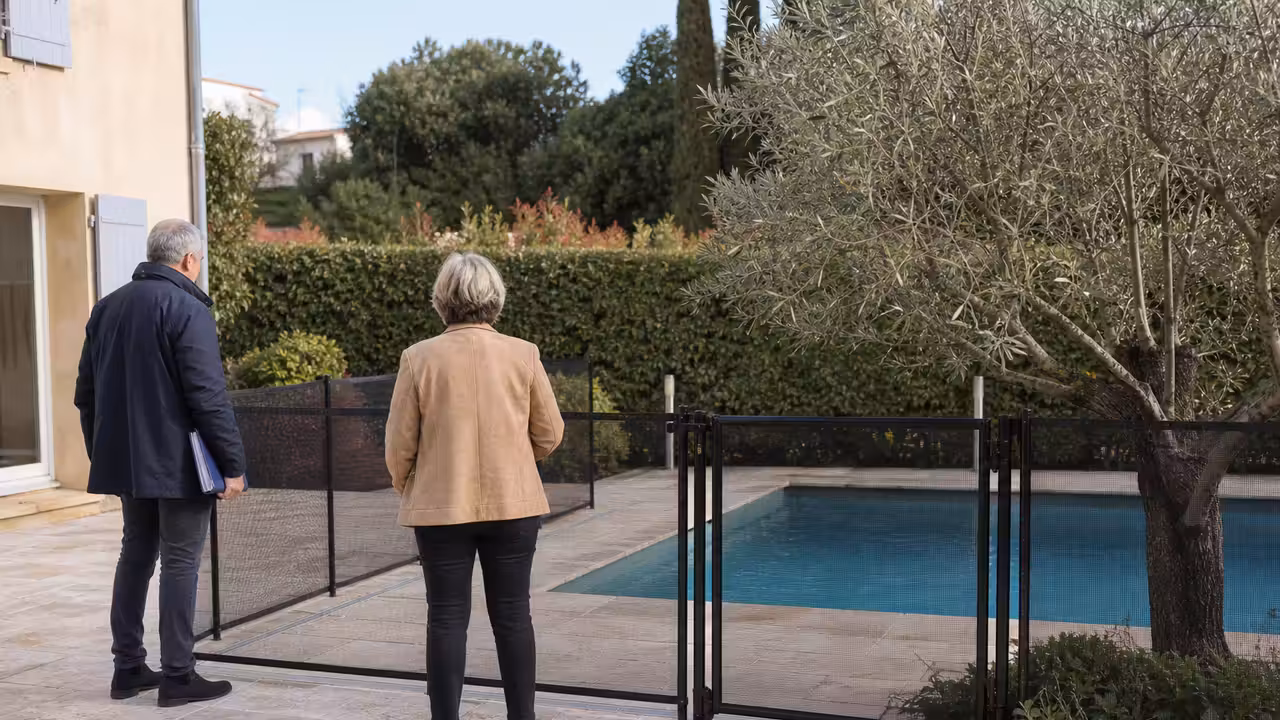 Propriétaires examinant une barrière de sécurité autour d’une piscine avant la vente de leur maison