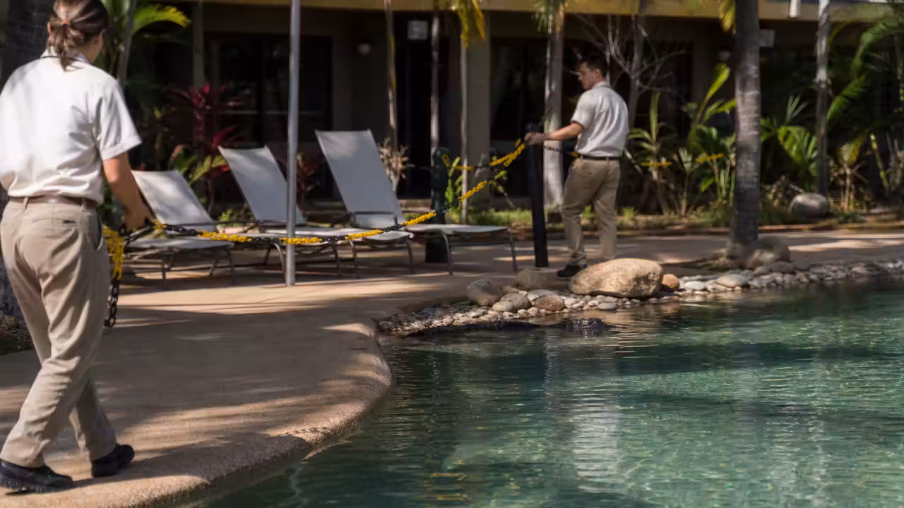 Piscine extérieure d’un hôtel tropical évacuée, avec personnel sécurisant les abords du bassin