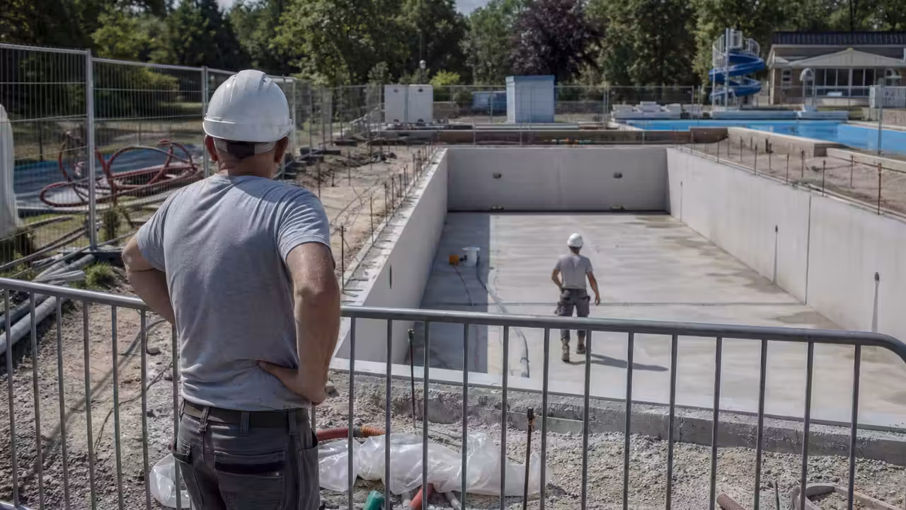 Chantier d’une piscine publique moderne avec bassin en construction et anciennes installations à l’arrière-plan