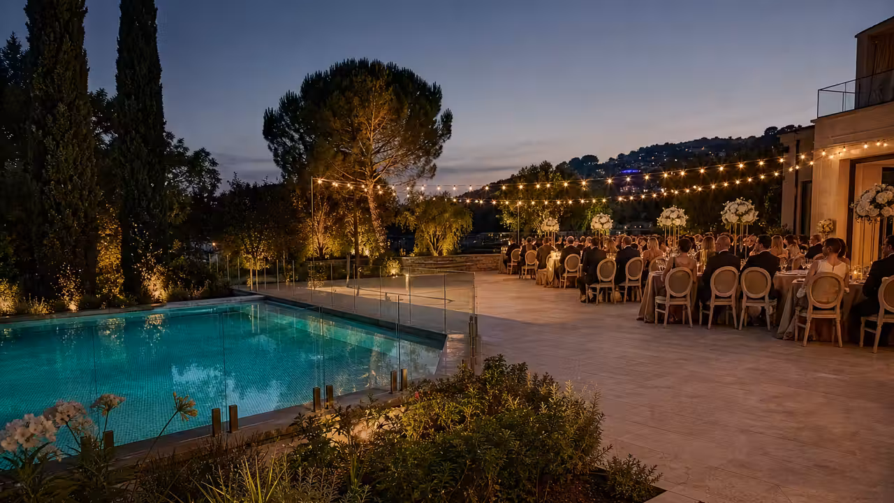 Réception de mariage élégante sur une terrasse, avec piscine éclairée et tables dressées au crépuscule