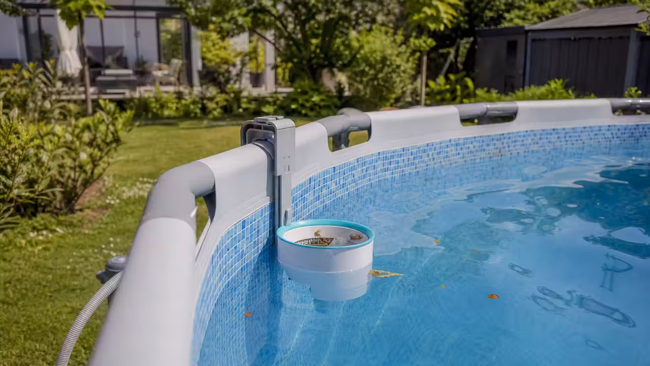 Skimmer suspendu fixé au rebord d’une piscine hors sol, retenant des feuilles à la surface de l’eau