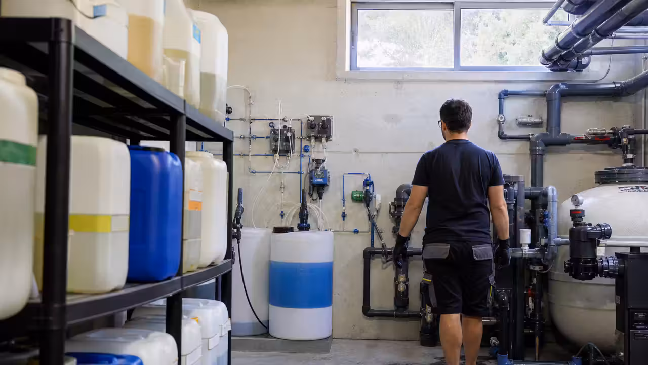 Local technique de piscine rangé avec bidons de traitement séparés et matériel de contrôle de l’eau