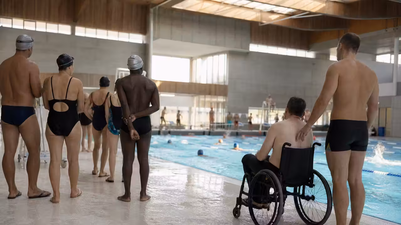 Participants de tous âges réunis près d’un bassin municipal lors d’un relais de natation solidaire et inclusif.