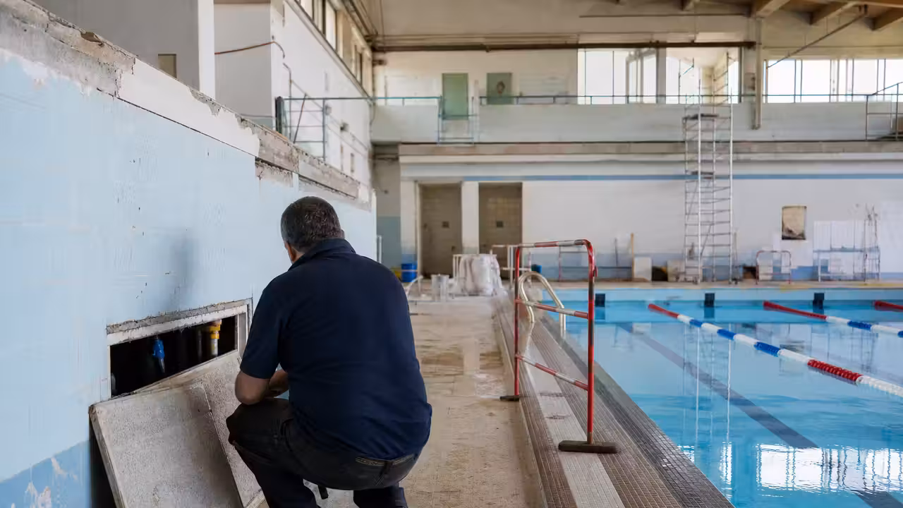 Bassin couvert d’une piscine publique avec lignes d’eau et vestiaires modernes en arrière-plan