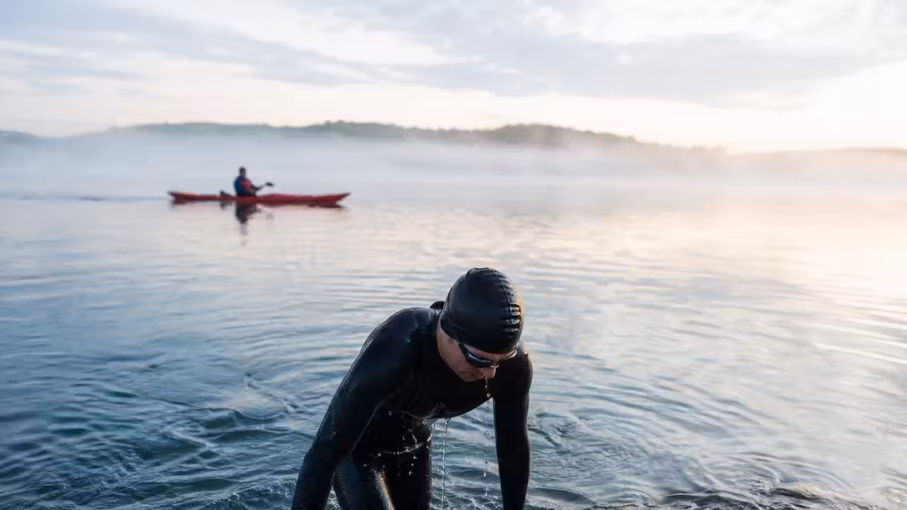 Nageur d’endurance en eau libre observant l’horizon avant une longue séance encadrée