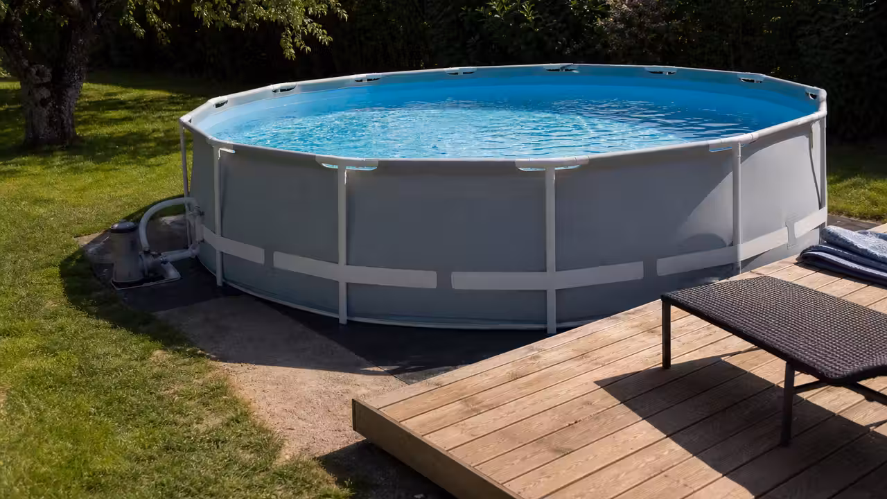 Piscine hors-sol tubulaire installée sur un terrain nivelé avec bâche, pompe de filtration et terrasse en bois