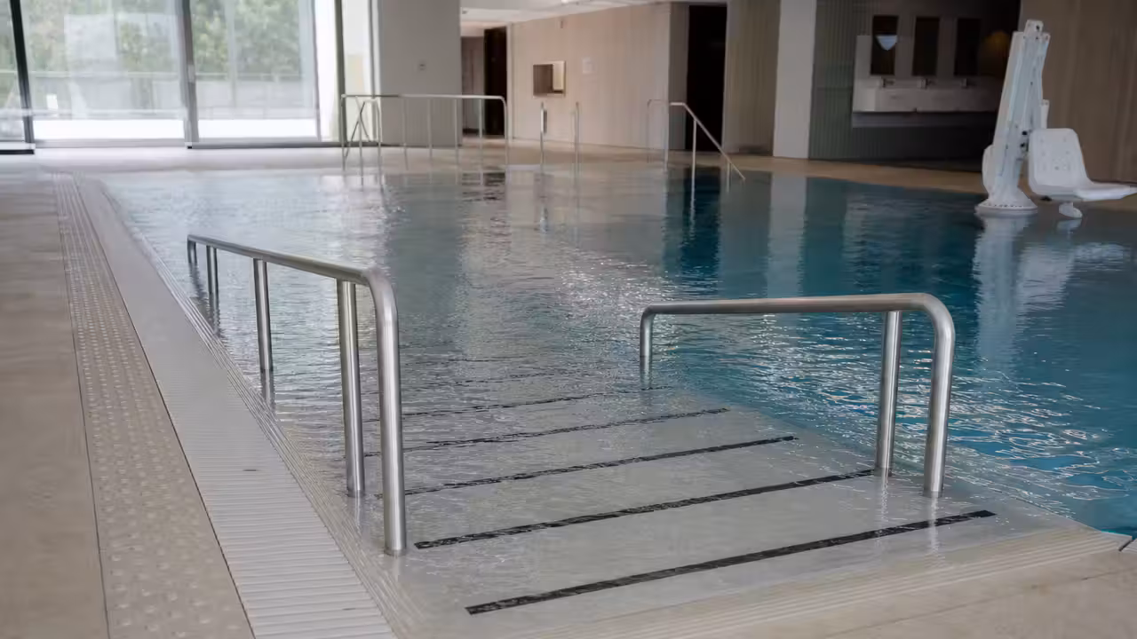Accès de plain-pied et rampe immergée dans une piscine publique lumineuse et accessible
