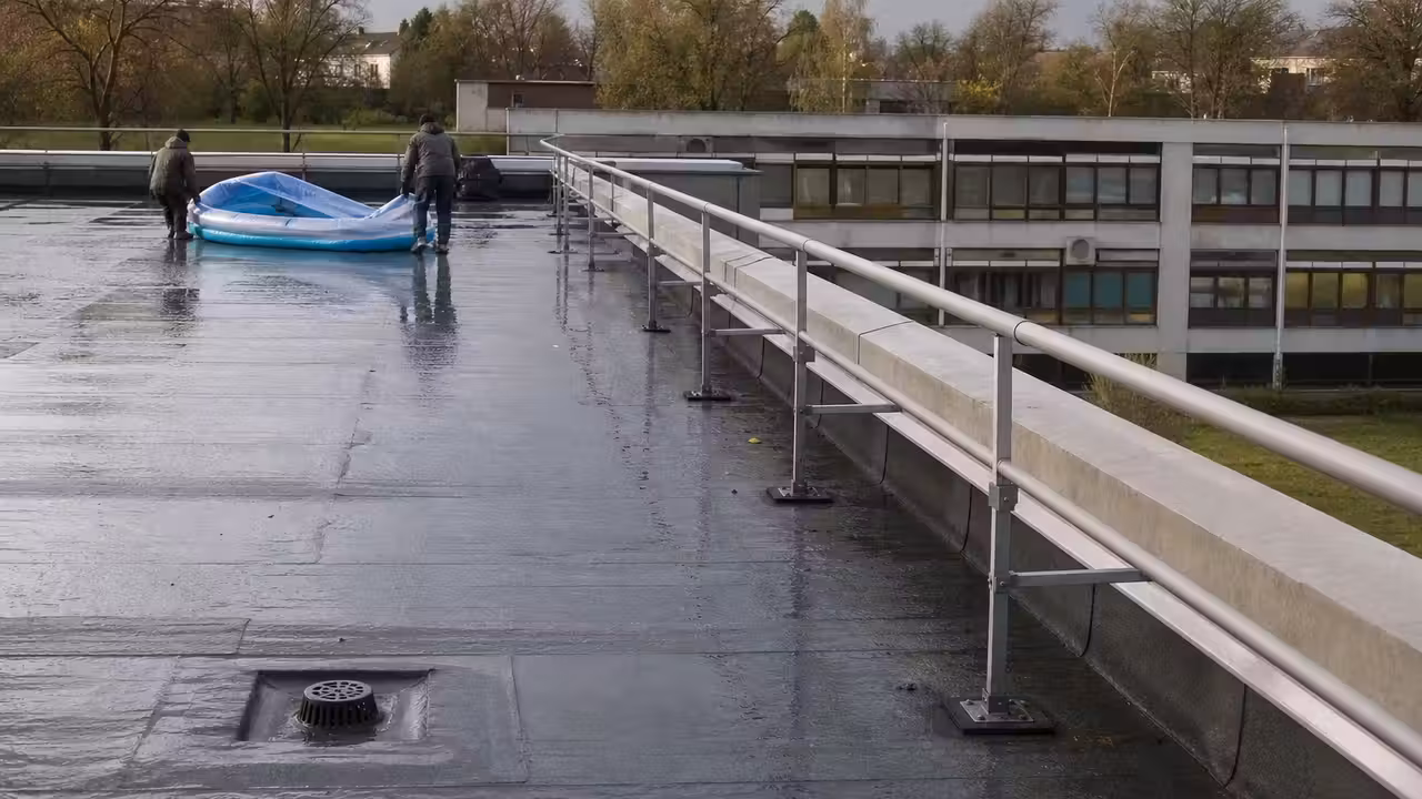 Toiture-terrasse d’un bâtiment avec bassin vide et ingénieur vérifiant la structure et les évacuations