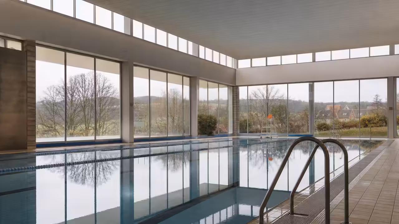 Vue intérieure d’un centre aquatique public avec bassin de nage, plages carrelées et lumière naturelle