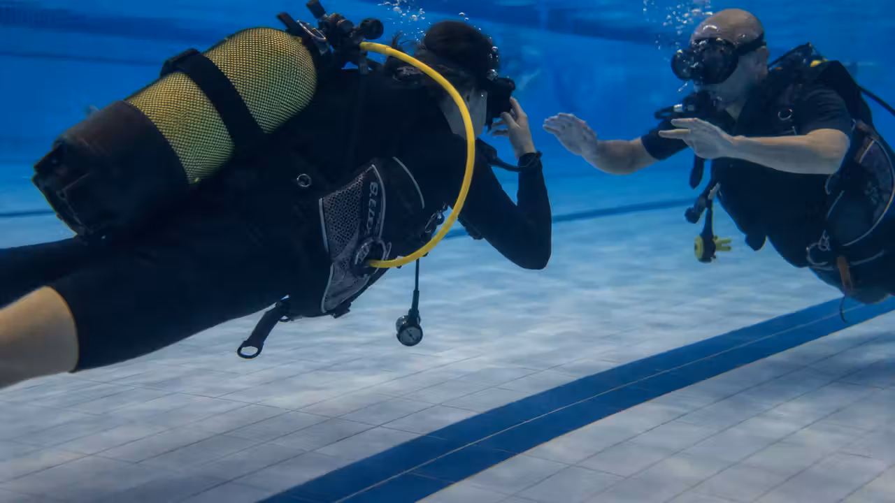 Plongeur débutant encadré par un moniteur lors d’une initiation en piscine couverte