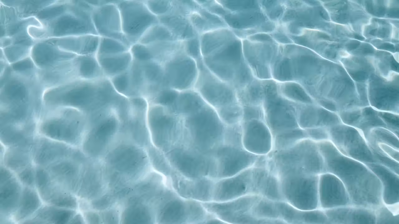 Bassin municipal vide avec plages en béton et zone de chantier sécurisée autour de la margelle