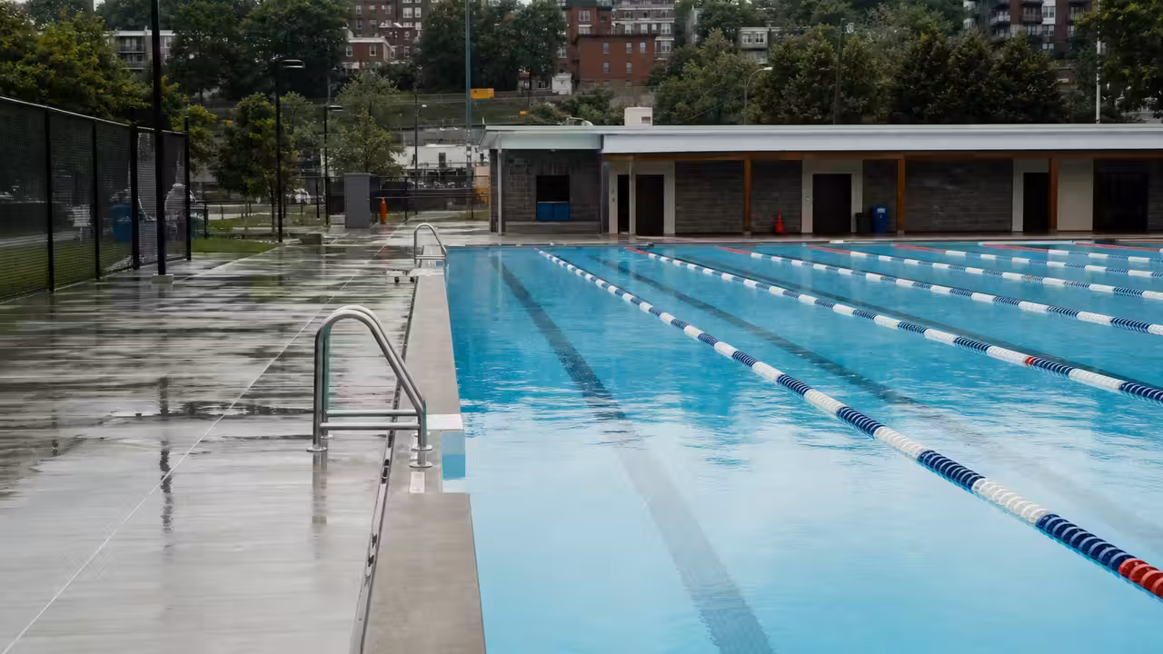 Bassin public extérieur vide au bord de l’eau, avec couloirs de nage et montagnes de Vancouver en arrière-plan