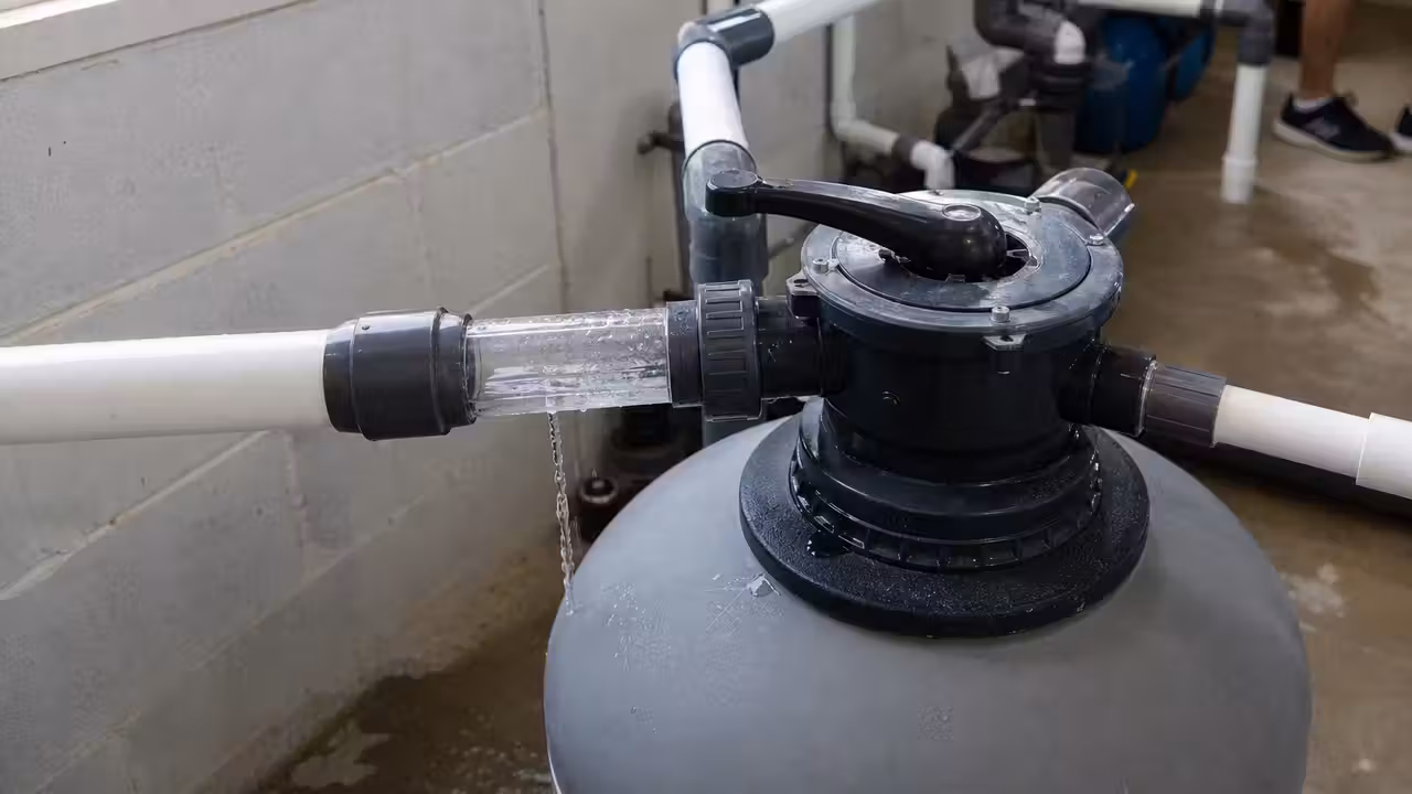 Vanne multivoies montée sur un filtre à sable dans un local technique, avec voyant de sortie égout