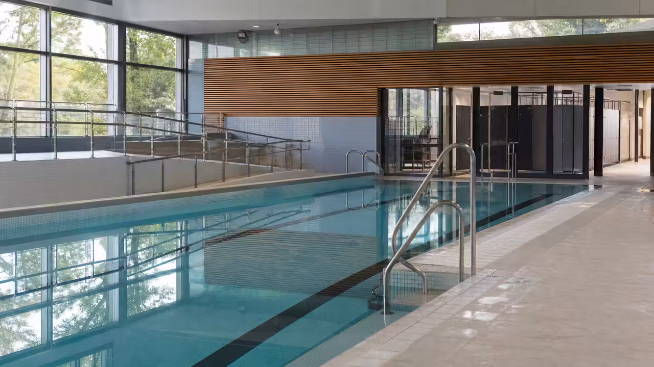 Vue intérieure d’une piscine municipale rénovée avec bassin, plages antidérapantes et vestiaires lumineux