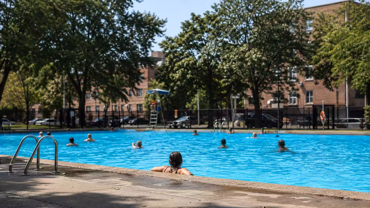 Bassin extérieur municipal animé à Montréal, avec zones ombragées et immeubles urbains en arrière-plan